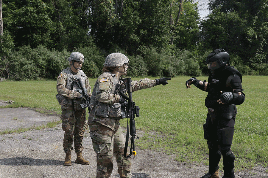 Two Soldiers interact with person in miltary black uniform