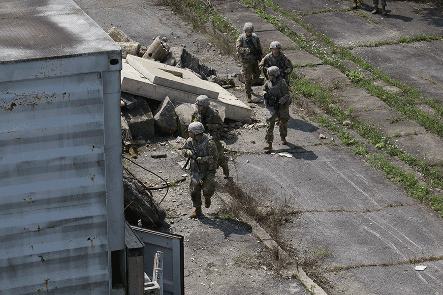 Soldiers scout around rubble.