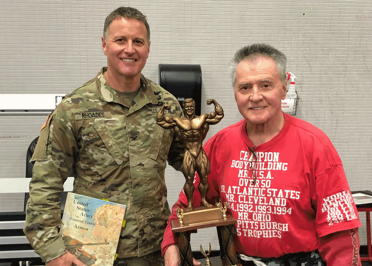 Ohio Army National Guard Brig. Gen. Stephen Rhoades stands with 74-year-old Jim McNeill, a powerlifter and bodybuilder holding trophy.
