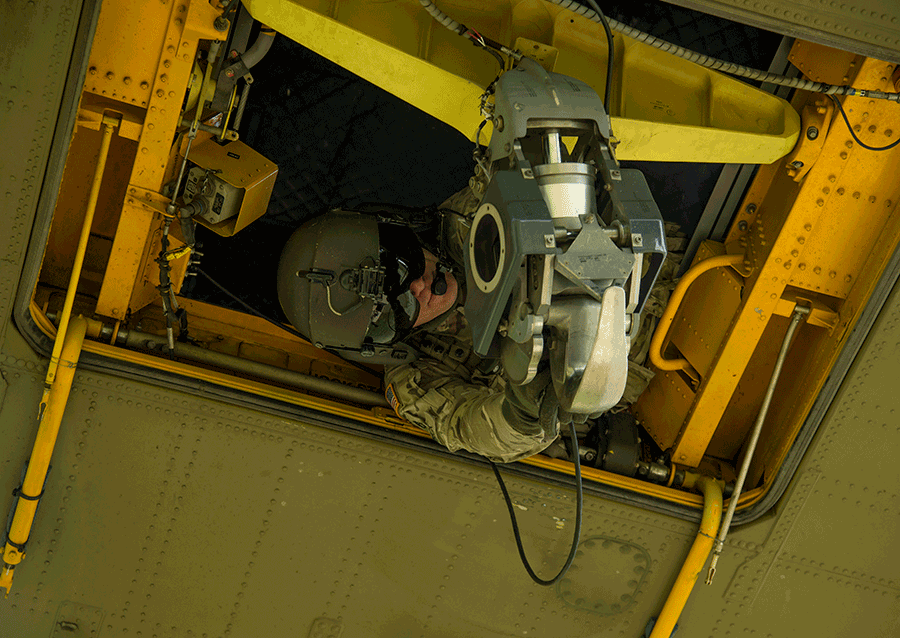 A crew member secures equipment beneath from inside a CH-47 Chinook helicopter.