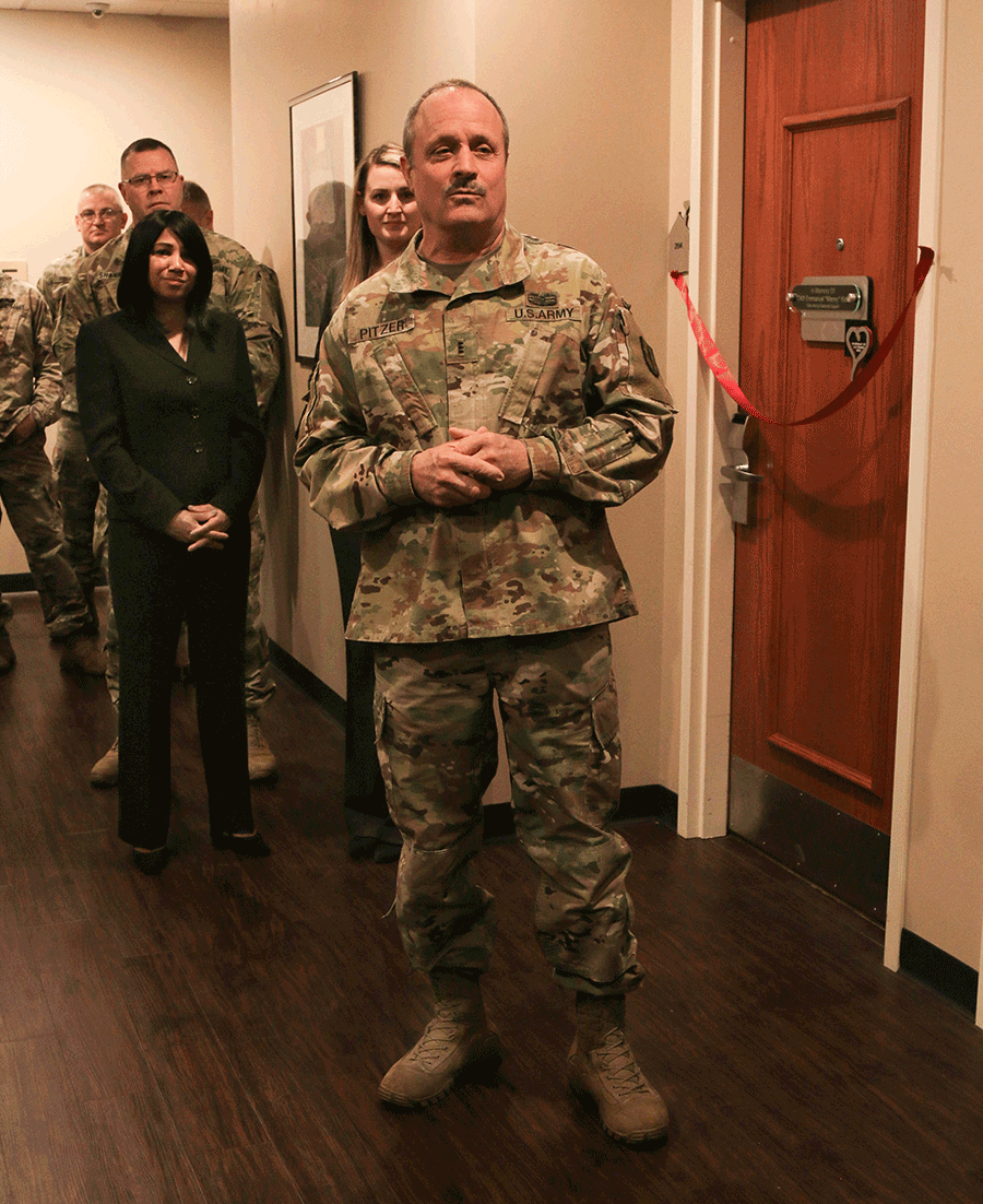 Chief Warrant Officer 3 Paul Pitzer addresses attendees in hall outside room 204.