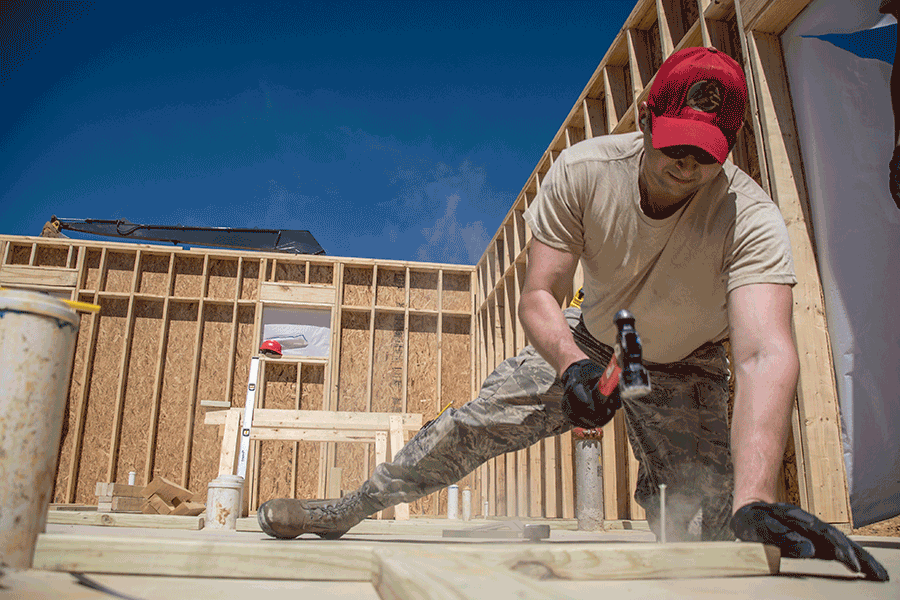 Tech. Sgt. Kenton Oakley builds cabin walls .