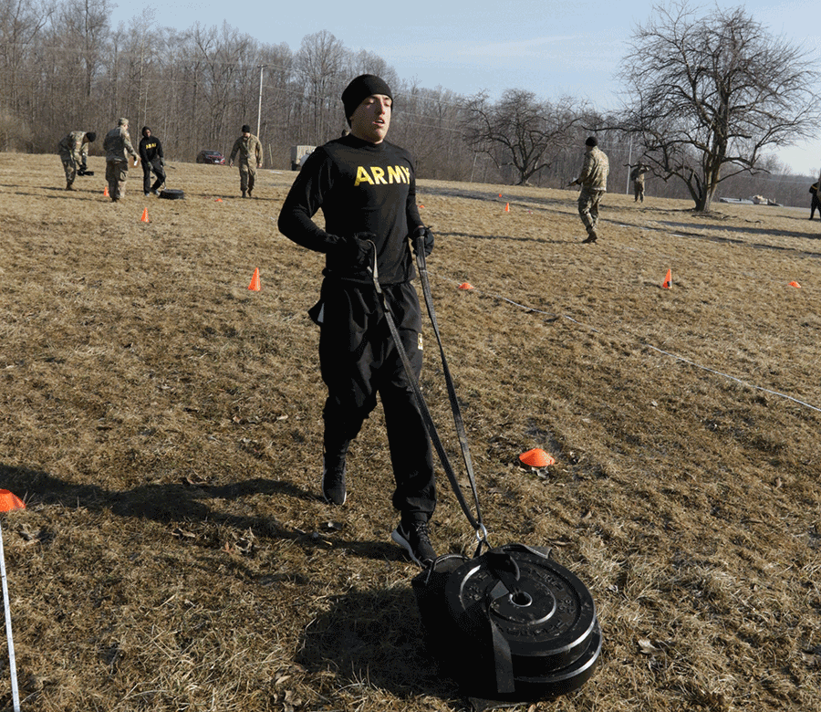 Soldier drags a weighted sled across field.
