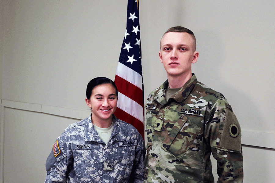 Male and female Soldier stand in front of American flag