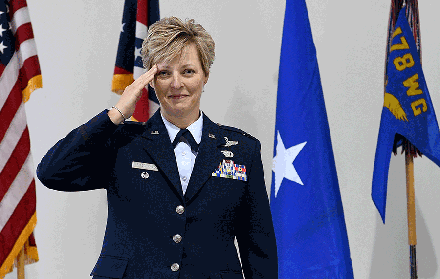 Col. Kimberly A. Fitzgerald salutes in front of the flags.