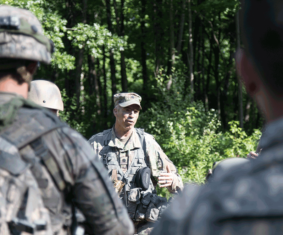 Lt. Col. talks to Soldiers in clearingof forest.