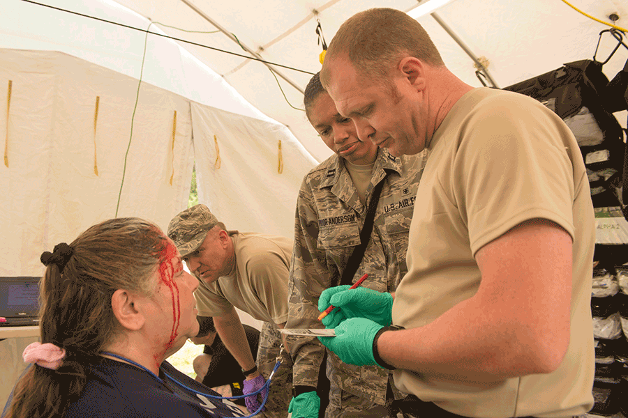 Air Guard members assess woman with head contusion inside tent.