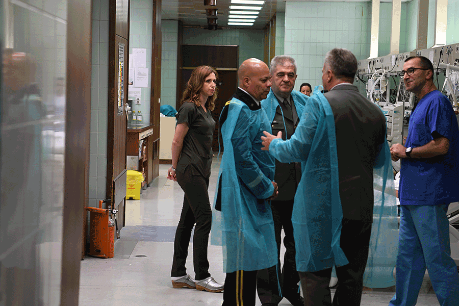 Maj. Gen. John C. Harris Jr. and others wear paper gowns while touring Military Medical Academy.