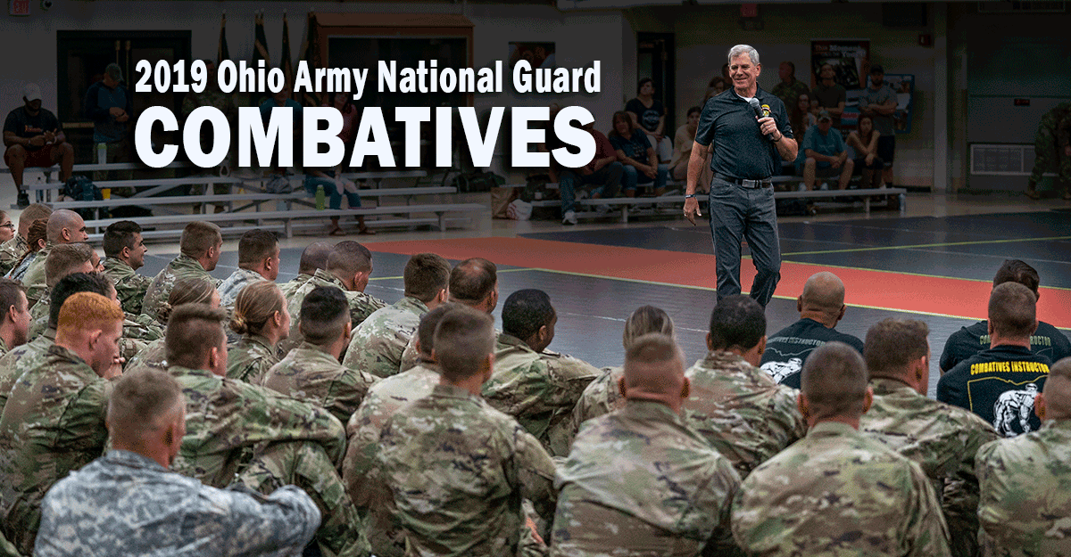 Retired U.S. Army Lt. Gen. Mike Ferriter addresses  competitors on bleachers from mat. 

