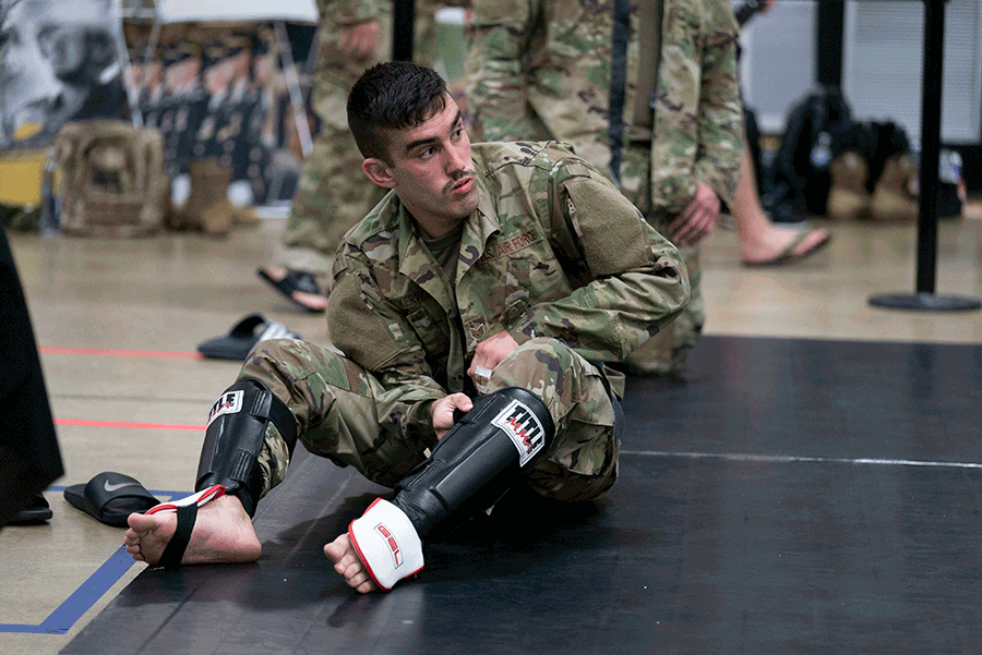 Airman adjusts knee guard sitting on mat