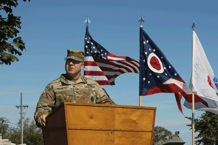 Col. Daniel Shank at podium with American and Ohio flags flying in background.