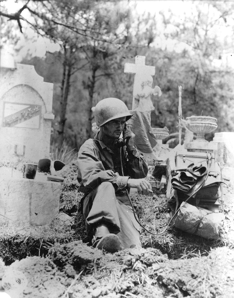 A radio operator is shown dug in at the cemetery.
