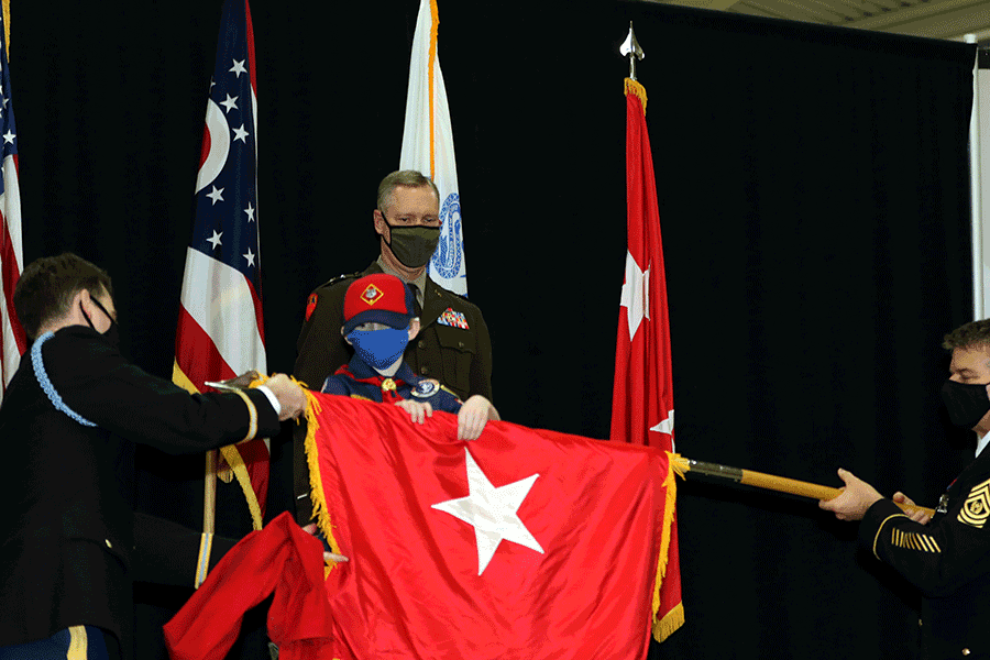 Ben Stivers helps unfurl a two-star flag while Steve Stivers stands behind him.