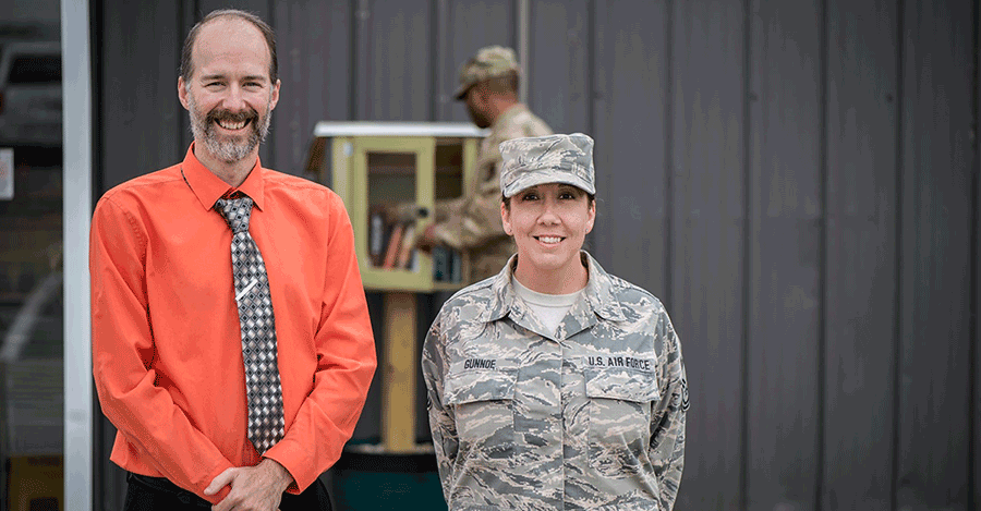 Chief Master Sgt. April Gunnoe with Chris May in front of 'mini library'.