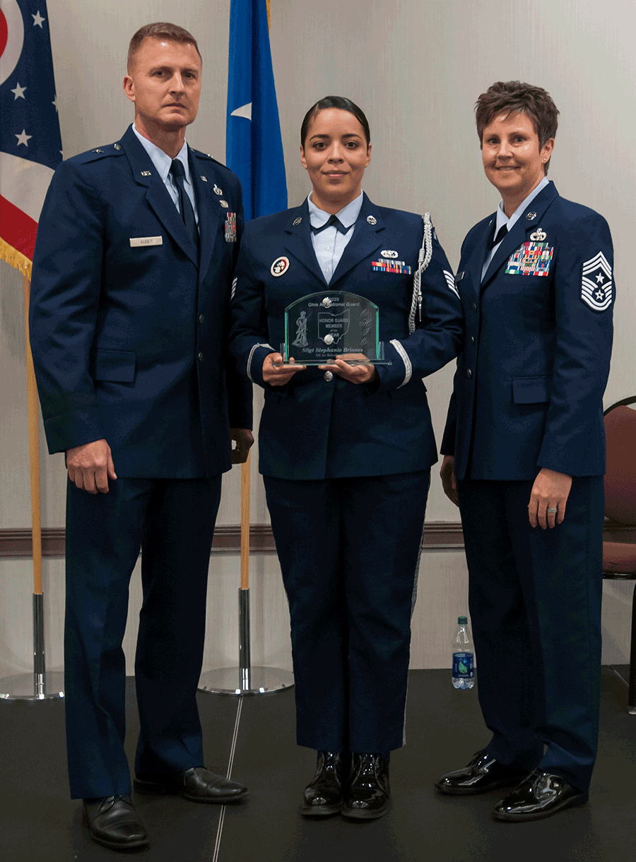 Airman stands with leadership holding award.