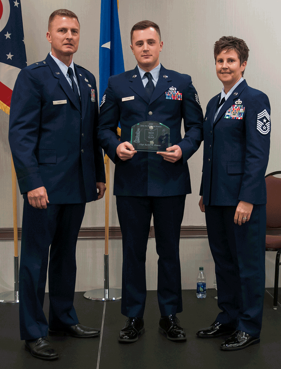 Airman stands with leadership holding award.
