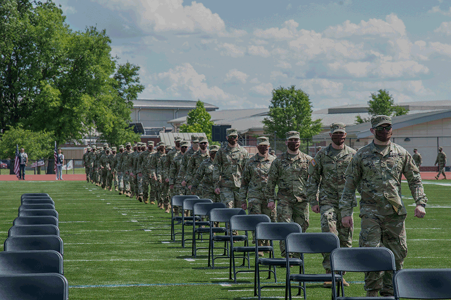 Soldiers march into football stadium.