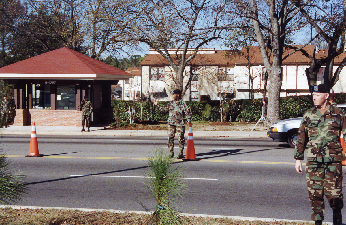 Soldiers stand guard by pylons in road.