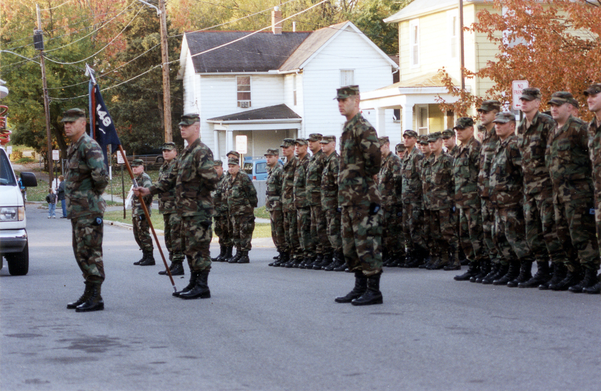 Soldiers stand at attention along street.
