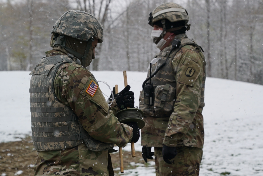 Soldiers in snowy clearing unrolling wire.