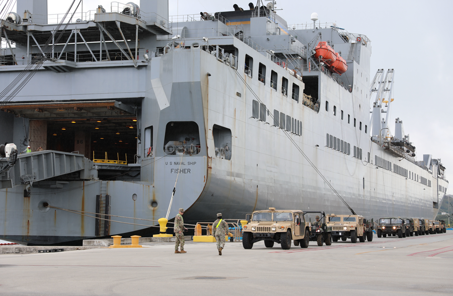 Soldiers and vehicles line up before loading onto the U.S. Naval Ship Fisher.