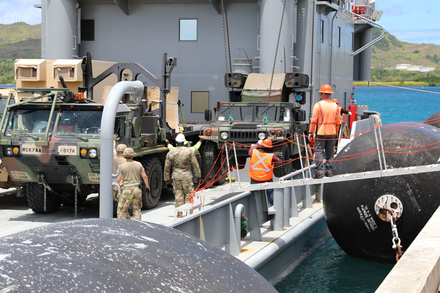 Soldiers and civilian contract workers load an Avenger Air Defense System onto an Army Watercraft System.