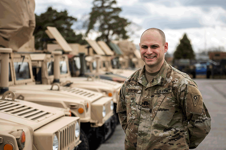 Capt. Tyler Craport stands for a photo in front of Humvees.