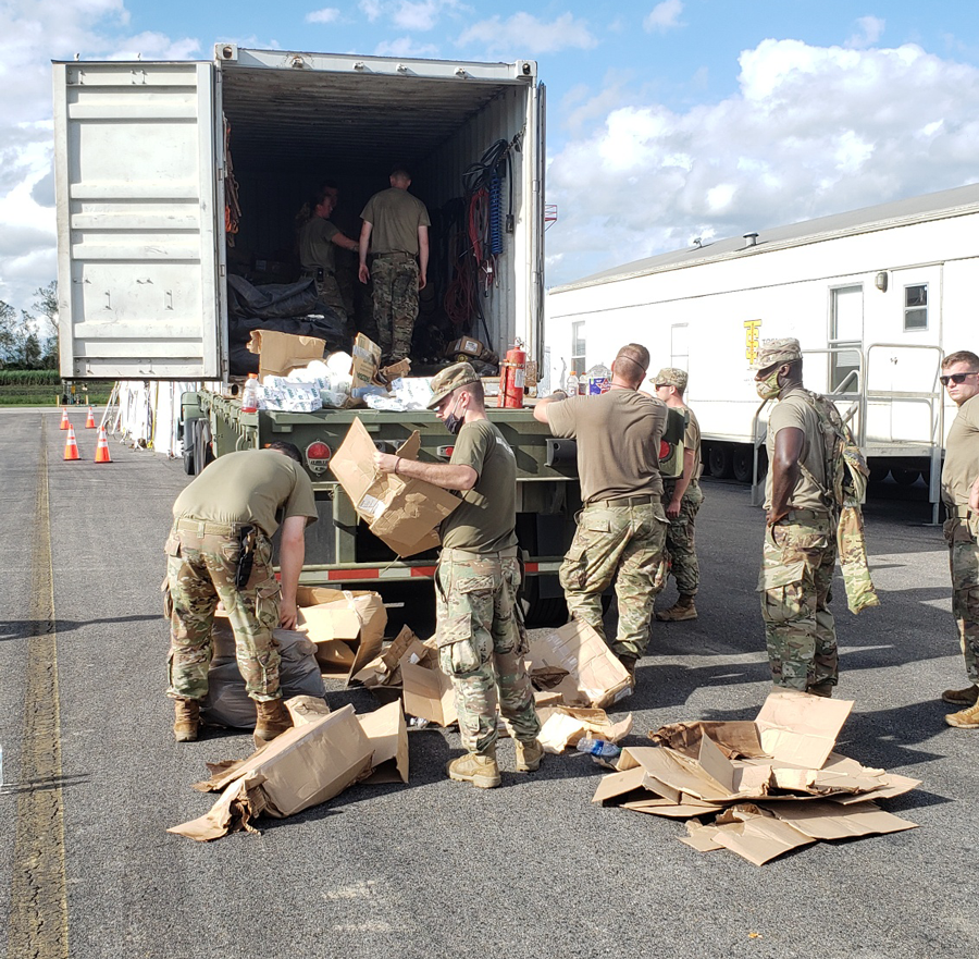 Soldiers help unload items off trucks.