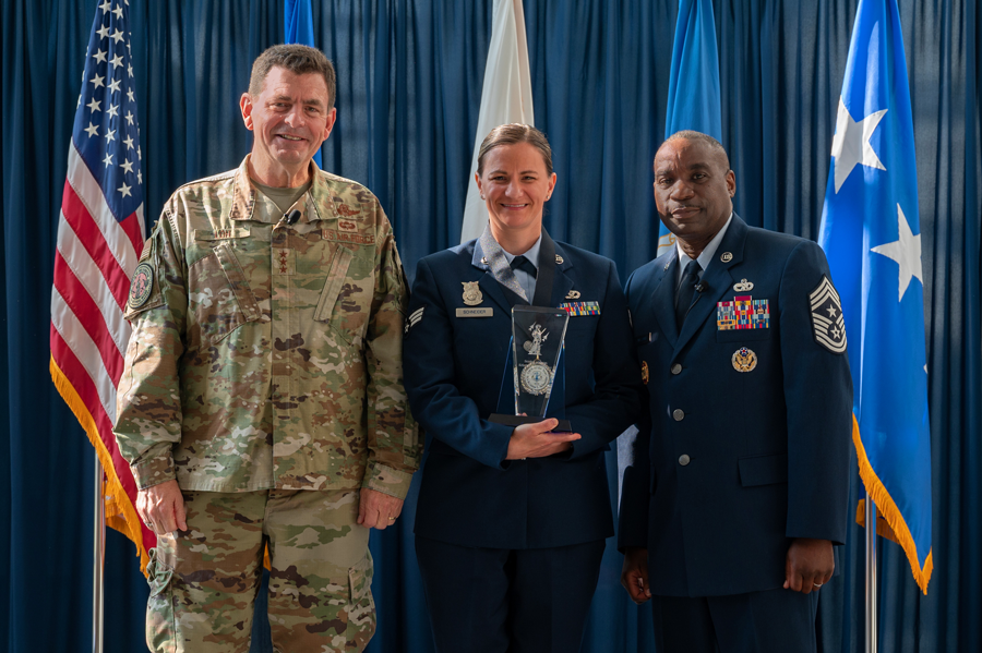 Schneider poses with award in middle of 2 other airmen.