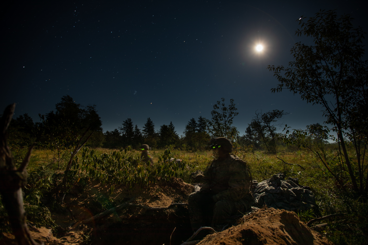 Soldiers in foxhole at night in moonlight.
