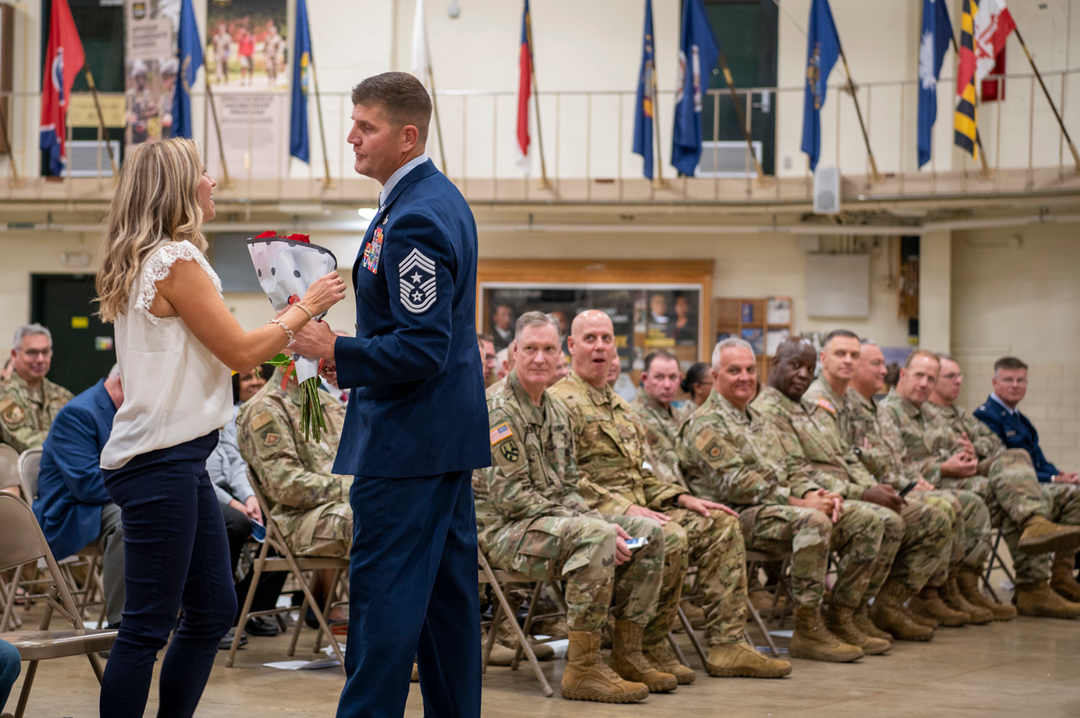 Taylor presents flowers to his wife in front of  guard members on drill floor 