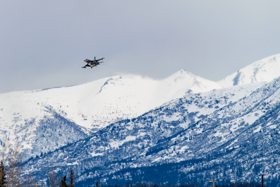 An F-16 in air over snow covered mountains in daytime.