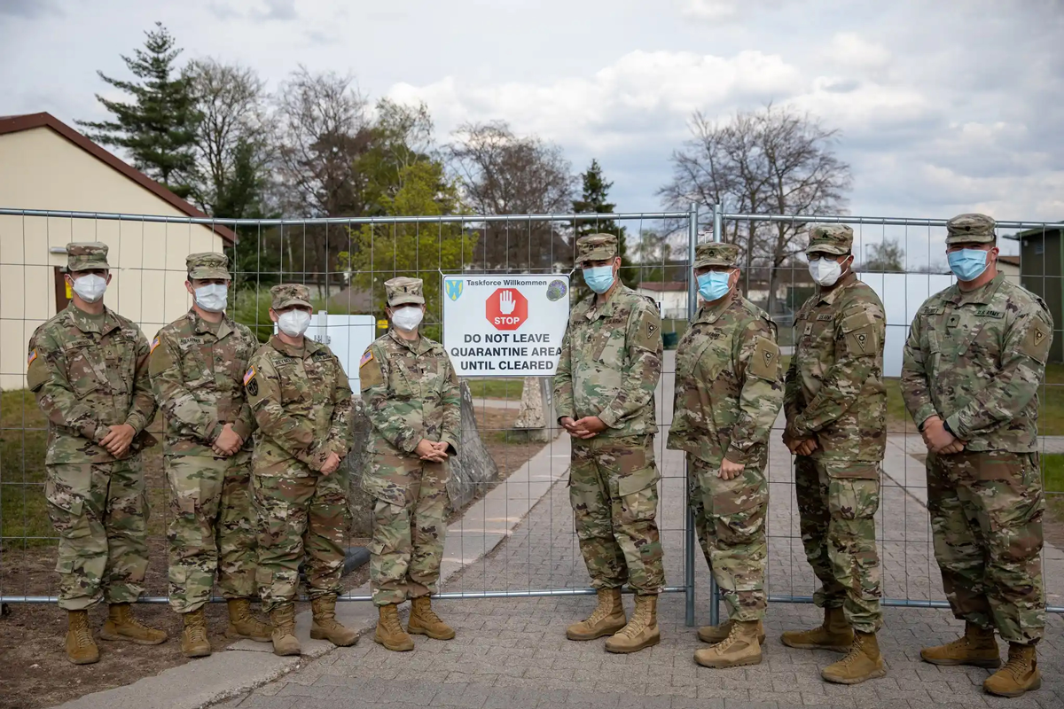 Soldiers pose in front of a gate.