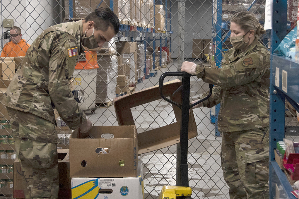 Airmen unpack banana boxes in warehouse.