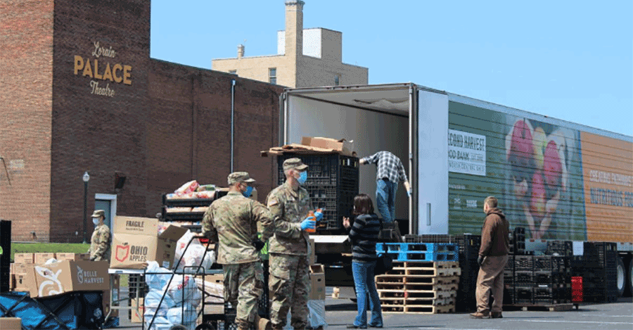 Soldiers work with civilians to unload and distribute semi.