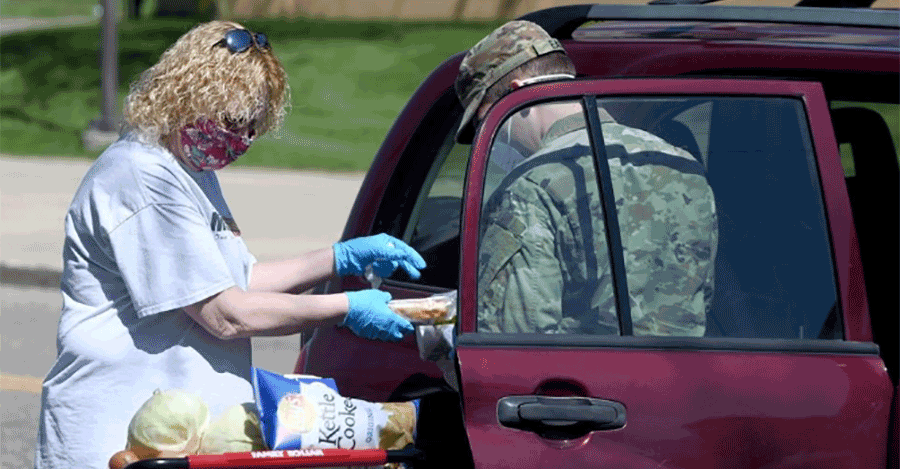 Soldier assists woman with groceries at SUV.