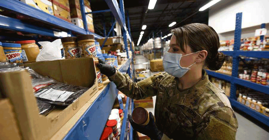 Female soldier pulls peanut butter from shelf in warehouse