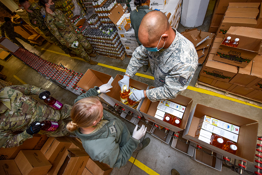 Soldiers fill boxes in assembly line.