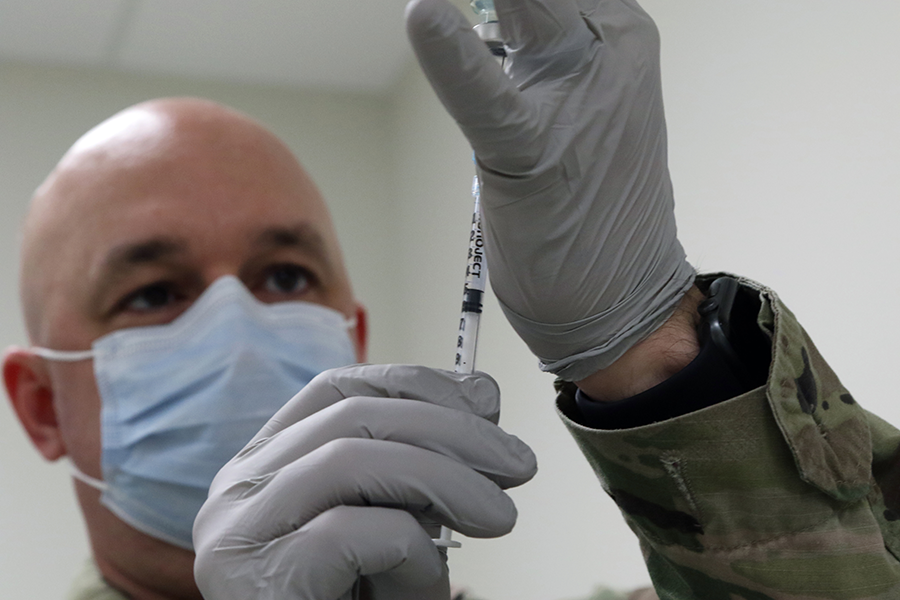 Capt. Christopher Warman draws up a dose of the Moderna COVID-19 vaccine.