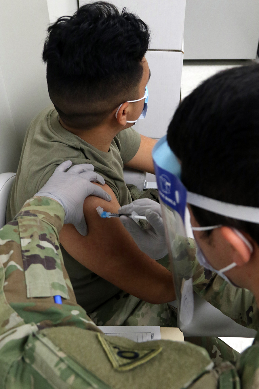 A combat medic administers a dose of the Moderna COVID-19 vaccine.
