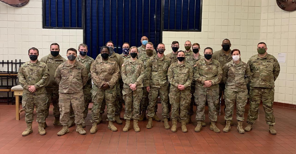 Soldiers stand for group photo wearing masks.
