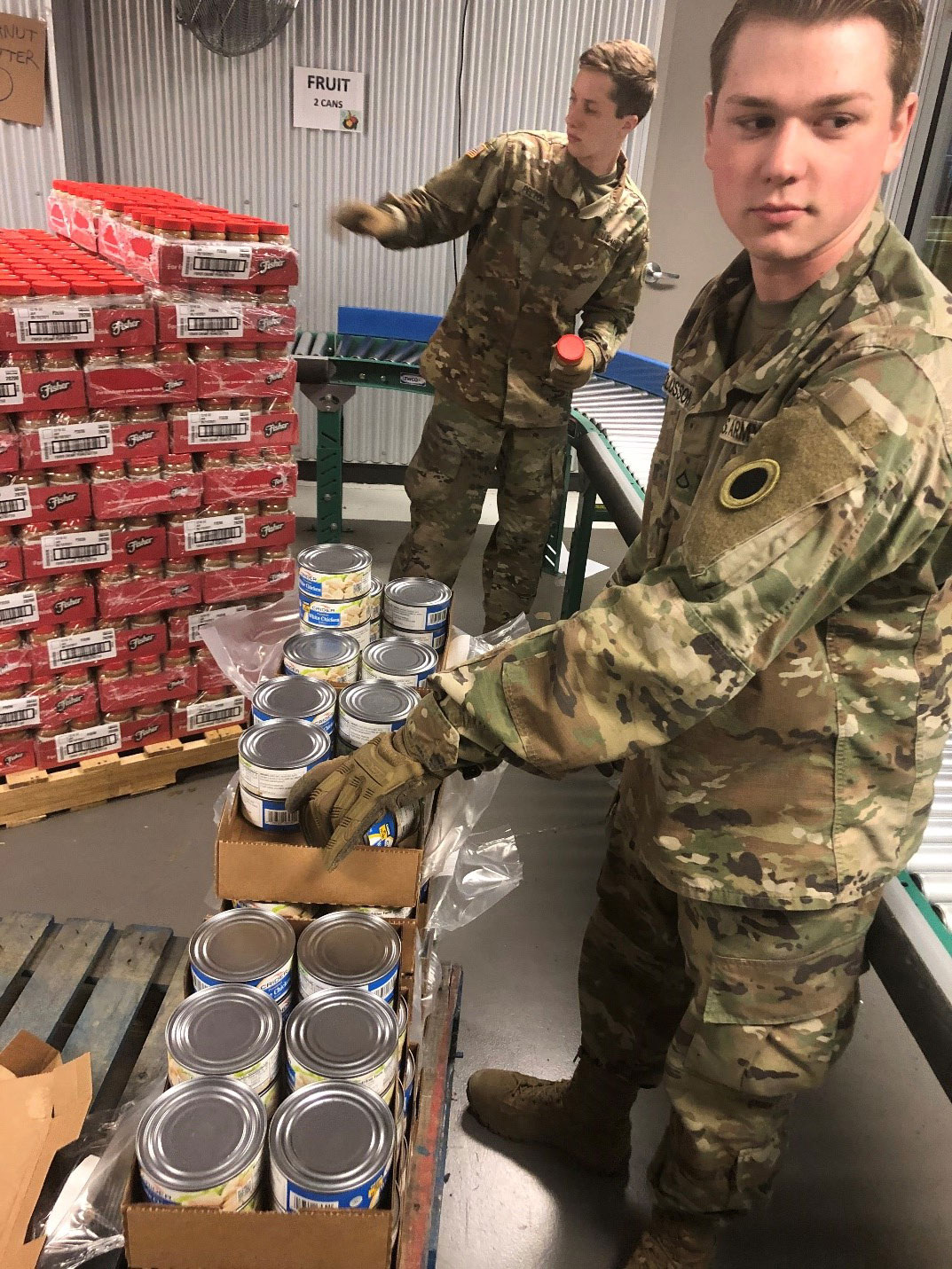 Soldier unloads canned chicken from boxes.