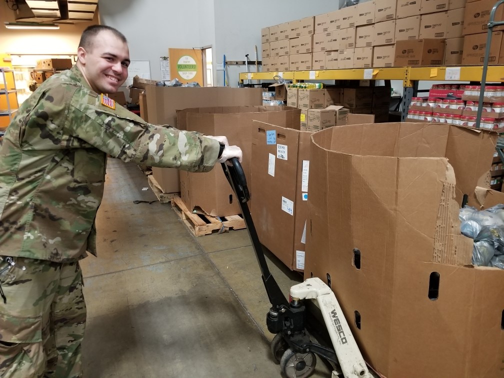 Soldier loads box of canned goods with dolly.
