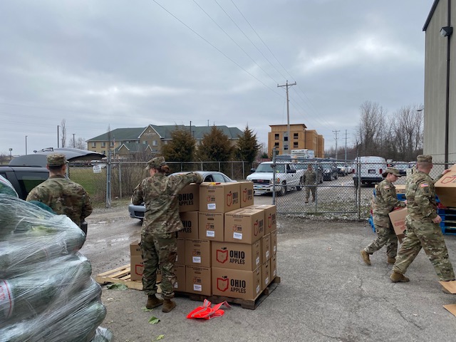 Soldiers unload pallet of apple boxes.