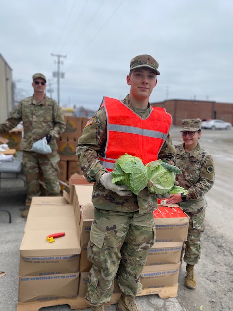 Soldiers pack produce and unlaod pallets.