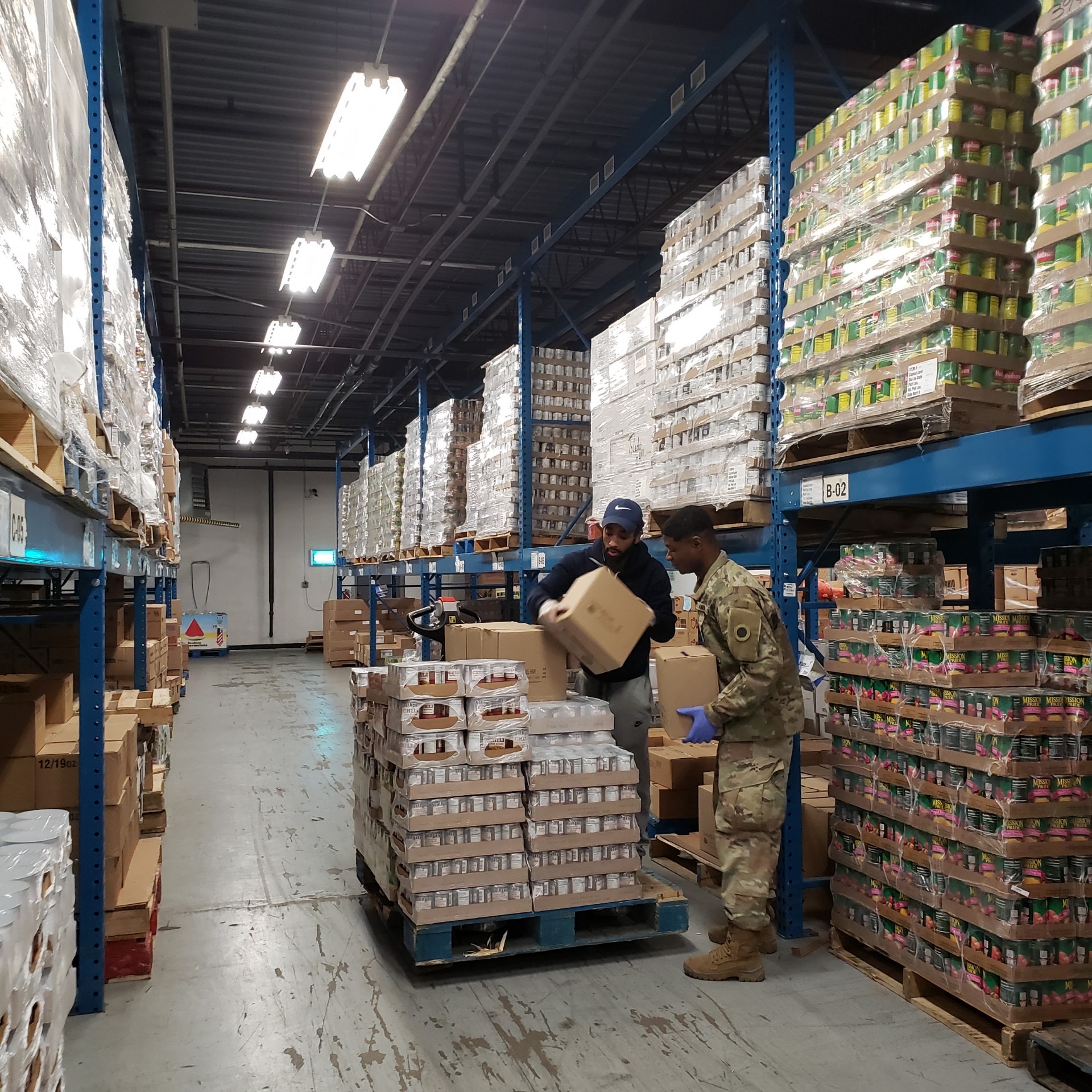 Soldiers unload pallet at warehouse.