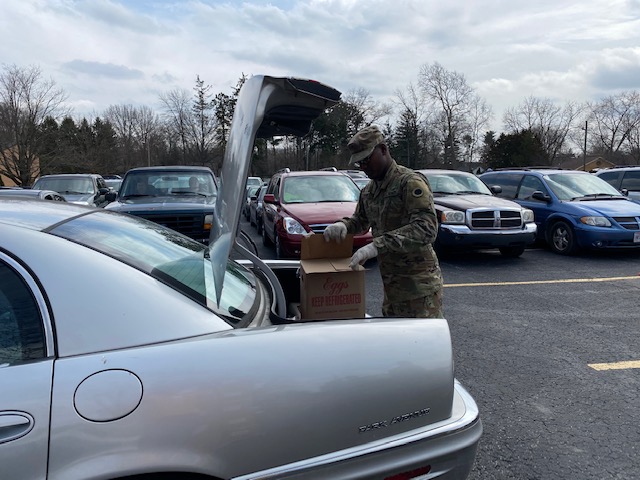 Soldier loads box into trunk.