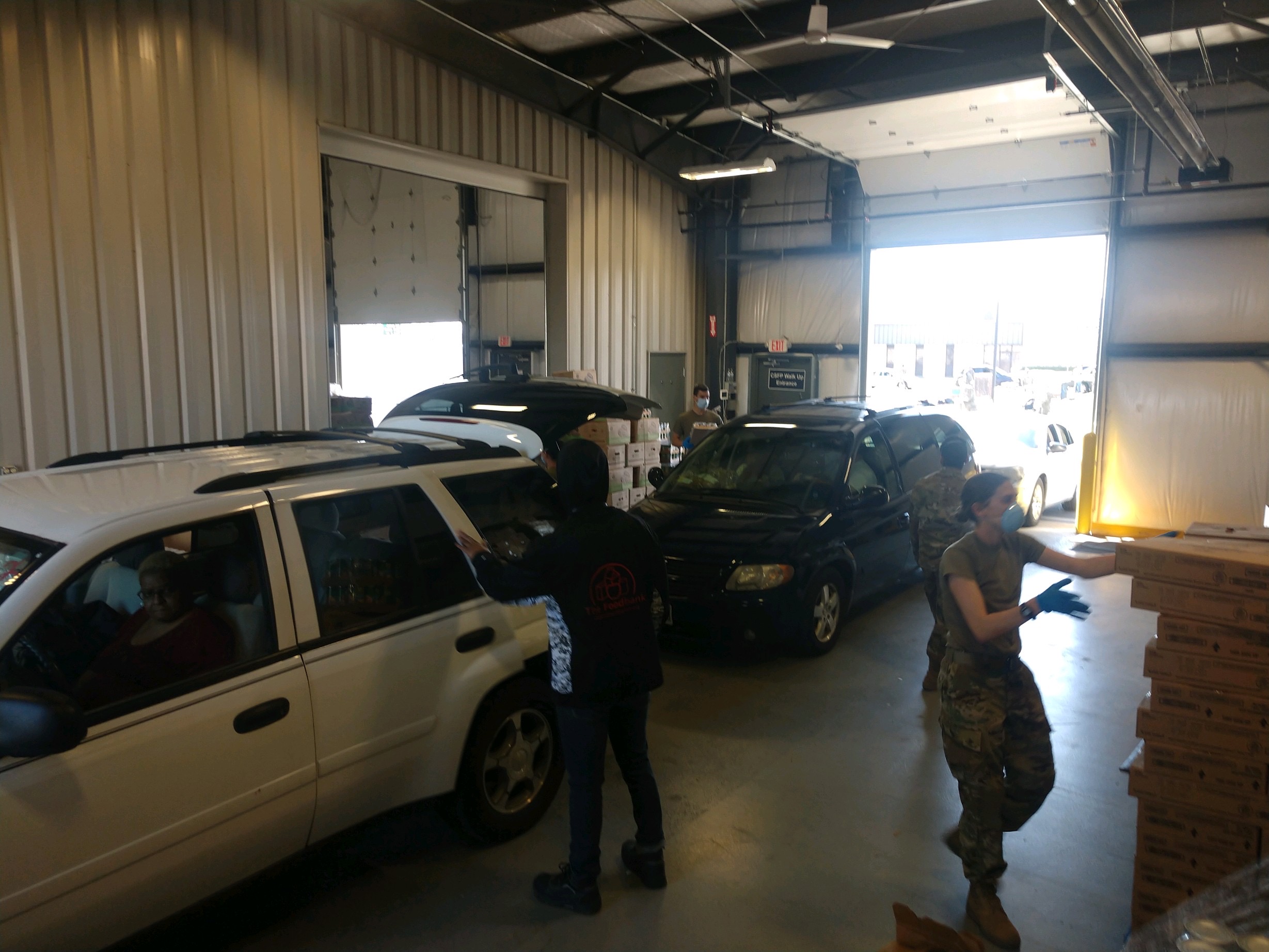 Soldiers load boxes into cars.